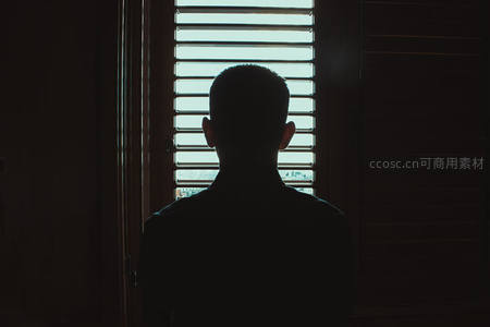 窗前剪影男子凝望城市晨光