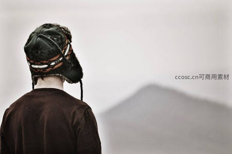 戴毛帽男子远眺朦胧山景