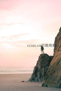 夕阳粉霞映照海岸，一人独立悬崖之巅