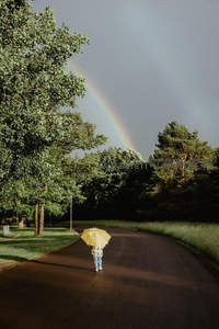 雨后彩虹下撑伞孩童独行林间小道