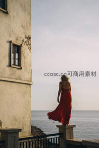 红裙女子伫立海边古堡俯瞰辽阔海景