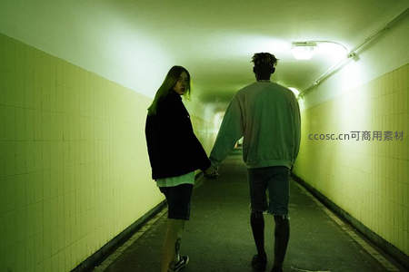 情侣牵手走过绿色灯光隧道