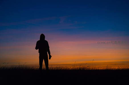 剪影人立黄昏草原，霞光映天际