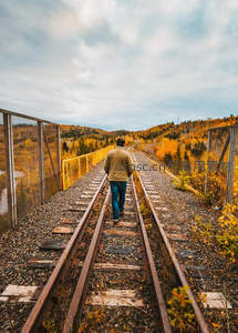 秋日铁轨上行走的背包客身影