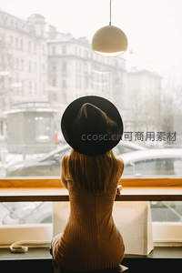 咖啡馆窗边，戴帽女子静观雪中街景