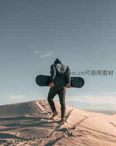 沙漠中怀抱滑板的旅人