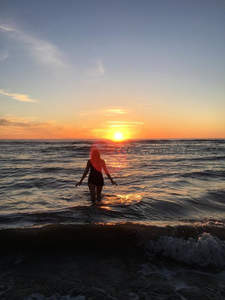 夕阳海浪中女子剪影漫步沙滩