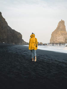 黄衣旅人漫步黑沙滩远眺海蚀奇岩