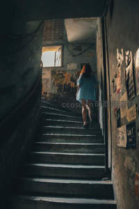 女孩拾级而上穿过斑驳光影的老楼梯