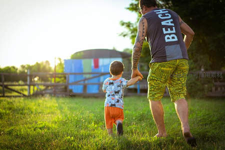 父子牵手漫步草地夕阳