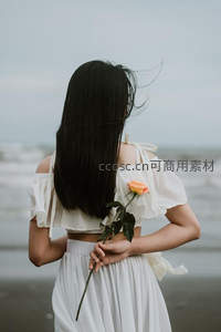 白裙女子海边持玫瑰沉思