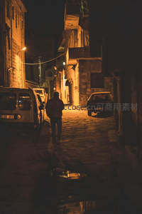 夜色小巷中独行者的温暖剪影