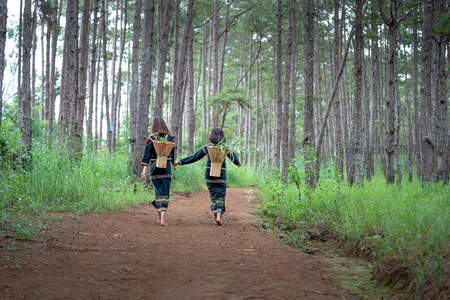 森林小径上两人牵手背篓漫步林间
