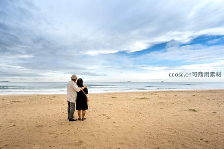 沙滩上老夫妻相拥远眺蔚蓝大海