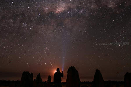 星空下的孤独旅人手持光束仰望银河