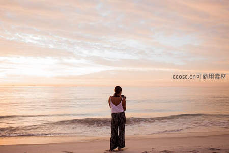 海边女子举相机，定格粉霞漫天的温柔时刻