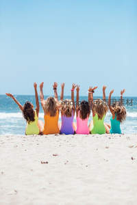 六位女孩沙滩排坐，彩色泳衣迎风举手
