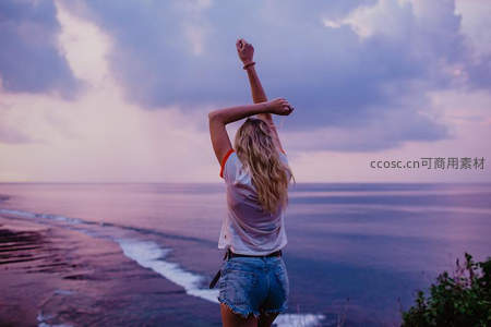 夕阳海岸女孩举手迎风起舞