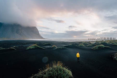 黑沙海岸孤影，黄衣旅人面对壮阔山海