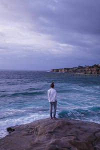 海边岩石上凝望波涛的沉思身影