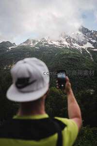 雪山之巅，旅人举起手机记录壮丽风景