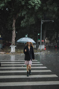 雨中少女撑伞走过斑马线