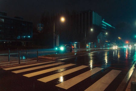 雨夜城市街角，车灯倒影映湿漉斑马线