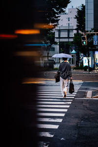 夜幕初降，撑伞行人穿越车流