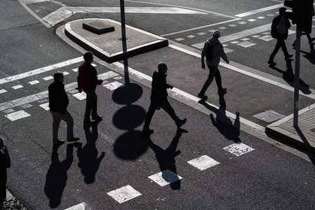 阳光下行人剪影与长长影子的几何美感