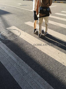 午后阳光下，两双脚步丈量斑马线的节奏