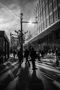 黑白光影中的都市步道，行人剪影拉长