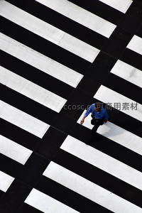 俯视视角下男子穿行黑白斑马线