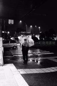 夜雨中孤影撑伞伫立街头斑马线