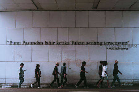 行人走过印有哲理名言的墙壁