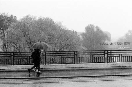 雨中情侣共撑伞漫步桥上