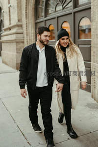 情侣牵手漫步于复古砖墙街道