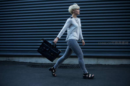 短发女子手提公文包疾行