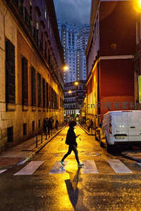 雨夜街巷行人匆匆，光影交错映城市