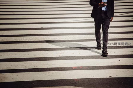 西装男士低头看手机穿越斑马线