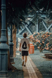 背包少年林荫小径散步赏花