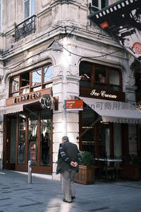 欧式转角咖啡馆前，老人驻足凝望街景