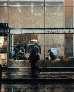 雨幕中的玻璃幕墙，行人撑伞匆匆走过都市角落