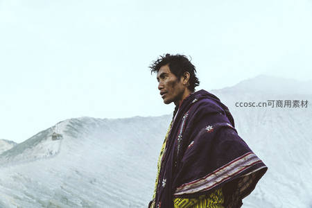 雪山脚下身披民族斗篷的男子
