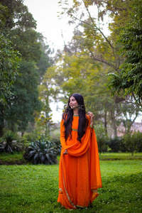 橙色纱丽女子漫步绿意盎然的花园中