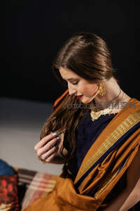 女子身着金边纱丽，佩戴珠宝凝神沉思