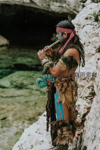 部落装扮吹笛者，岩洞旁神秘仪式