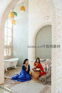 三位女子着华服围坐庭院共享美食