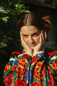 少女穿彩绣民族衣，双手托腮微笑