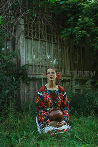 女子着花衣坐草丛，怀抱陶罐望远方