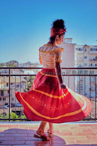 红裙舞者阳台旋转，城市天际线为幕